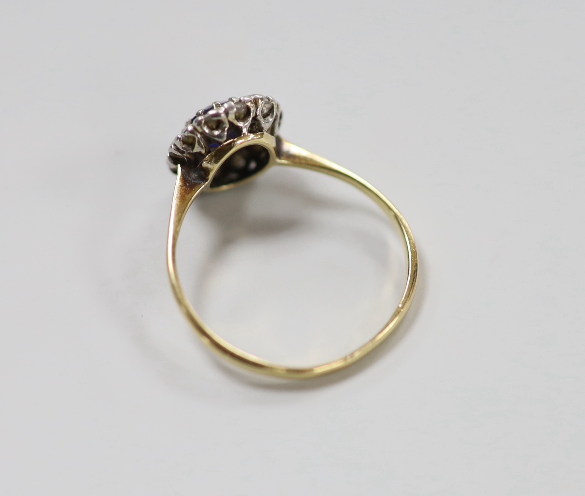 A yellow metal, sapphire and diamond set oval cluster ring, size Q, gross weight 2.8 grams.